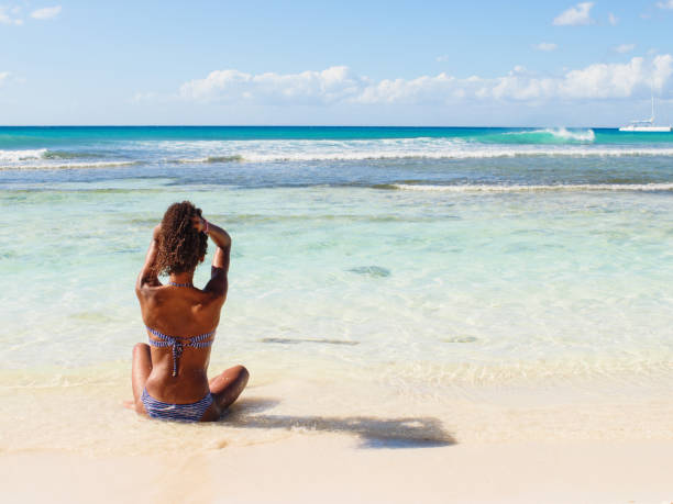istock Woman sitting on the beach 909874592
