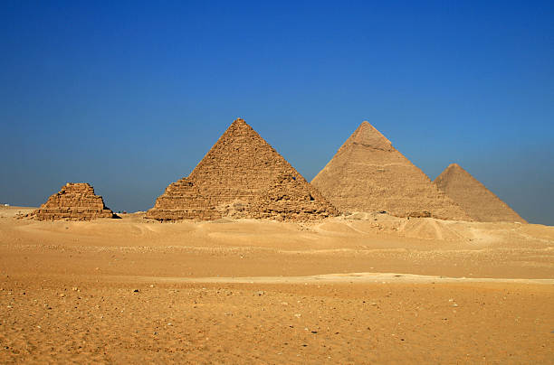 Silhouette of the Great Pyramids of Giza at sunset with a dramatic sky in the background