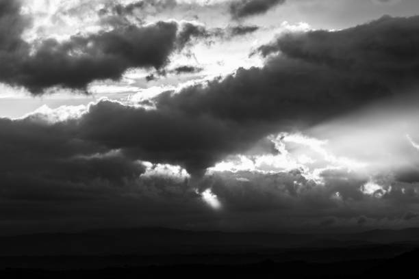 istock Sunset over a valley, with sun rays coming out through some clouds 909883156