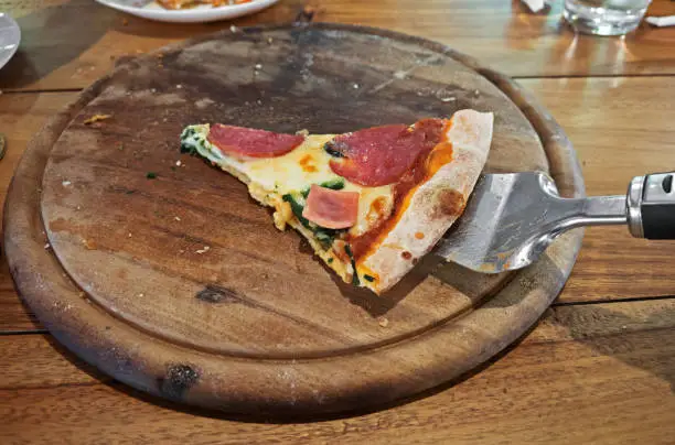 Closeup One Piece of Pizza Left on Wooden Tray