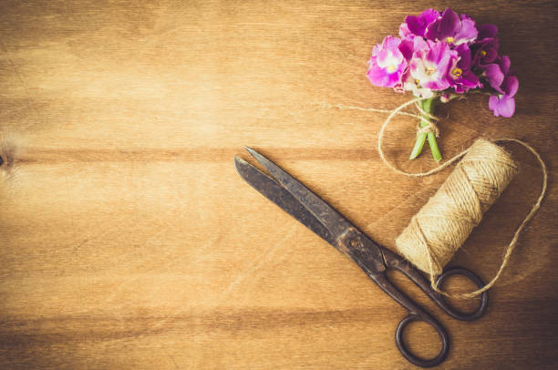 Tools and accessories for handicrafts or gift wrapping: bonsai scissors, jute rope, leather ribbon and spools  in vintage wooden box on dark wooden background