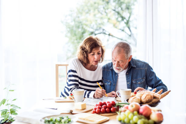 Senior couple eating breakfast at home. Senior couple eating breakfast at home. An old man and woman sitting at the table, relaxing. crossword stock pictures, royalty-free photos & images