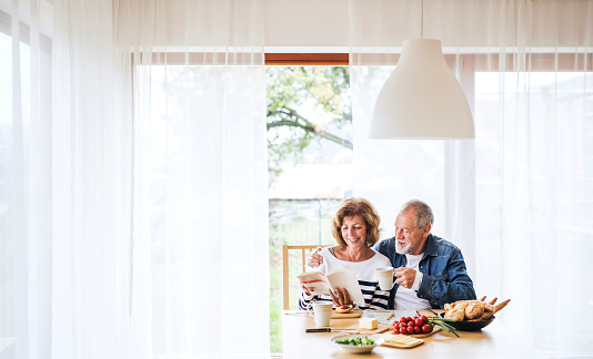 Senior couple eating breakfast at home. An old man and woman sitting at the table, relaxing.