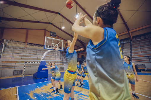 Group of women, playing basketball game indoors in arena.