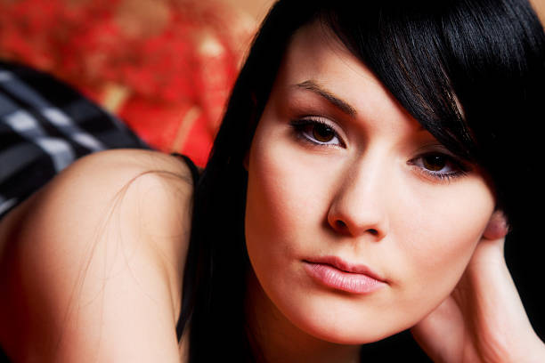 Portrait of a beautiful 18 years old young woman playing with hair. Over a red background.