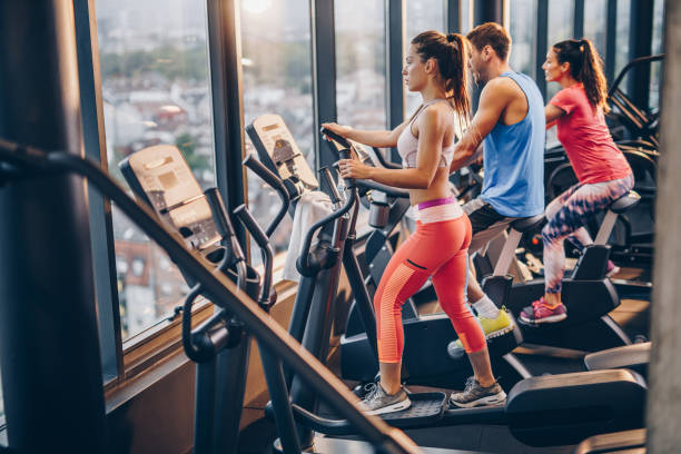 istock Group of athletic people warming up on exercise machines in a gym. 909895578