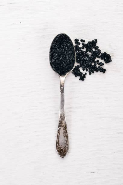 istock Spoon with black caviar on a wooden background. Top view. Free space for text. 909896608