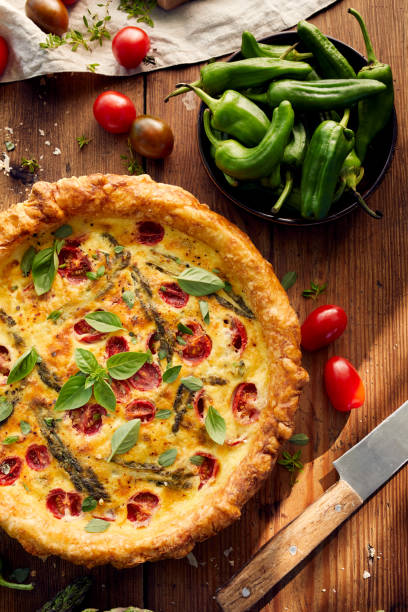 istock Quiche with cherry tomatoes and green asparagus on a rustic wooden table 909905990