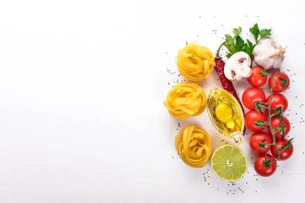 Dry Pasta tagliatelle, fettuccine with vegetables On a wooden background. Italian Traditional Cuisine. Top view. Copy space.