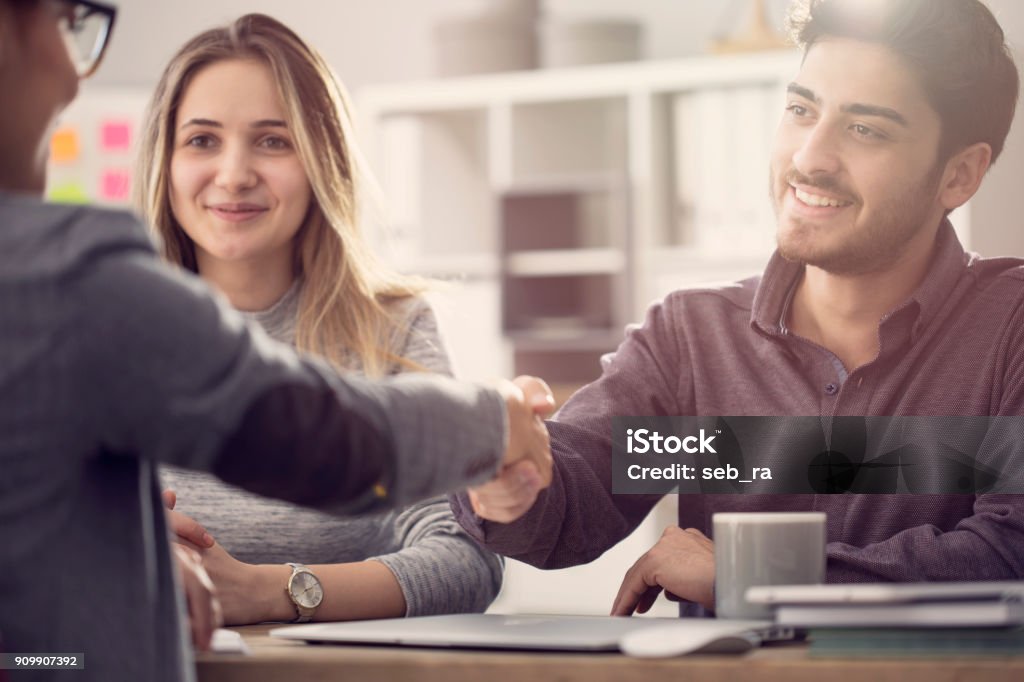 Young couple shaking hands with a female agent Bank - Financial Building Stock Photo