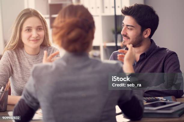 Photo libre de droit de Jeune Couple Discutant Avec Un Agent Féminin banque d'images et plus d'images libres de droit de Client - Client, Réunion, Activité bancaire