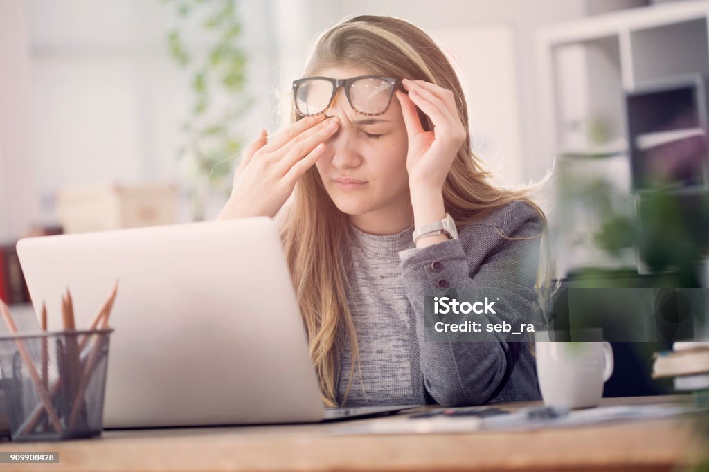 Young tired working woman at work Eye Stock Photo