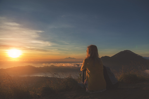 Girl watching the sunrise from mount Batur, Bali - Indonesia.