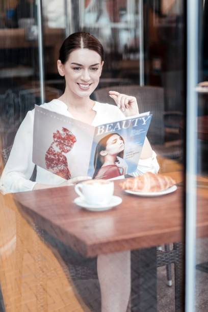 istock Happy brunette reading glossy magazine 909914234