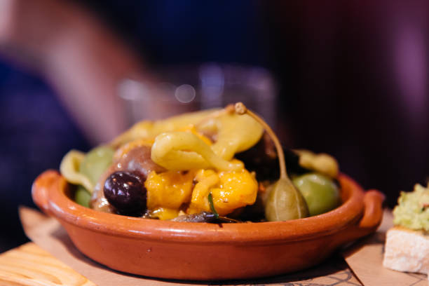 istock Green olives and yellow peppers in a ceramic bowl 909919420