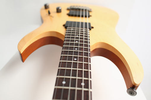 Classic shape wooden electric guitar with rosewood neck closeup. Six stringed learning lesson musician school education art leisure electrical vintage stage wood guitar concept