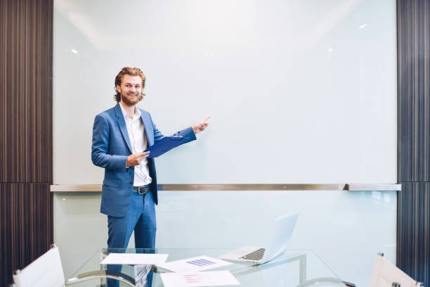 istock Blonde business man presenting a project on blank glass board 909926714