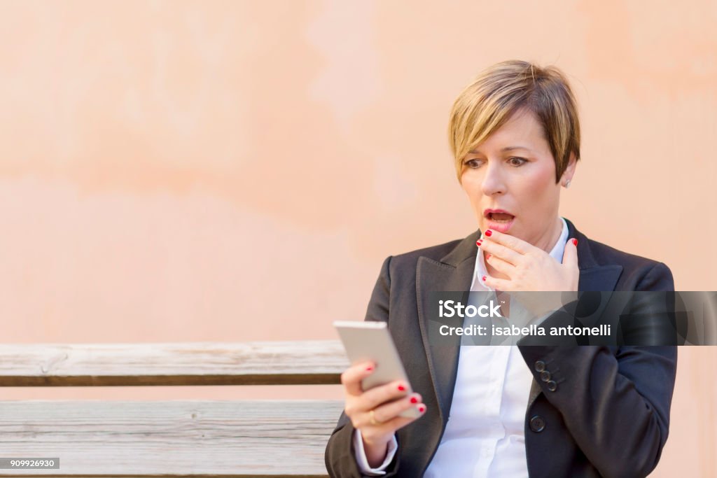 Surprised business woman calling by phone outdoor Surprised business woman calling by phone outdoor ( business concept ) Adult Stock Photo