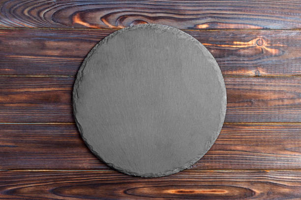 istock Round slate stand board a wooden background. space for text 909927424