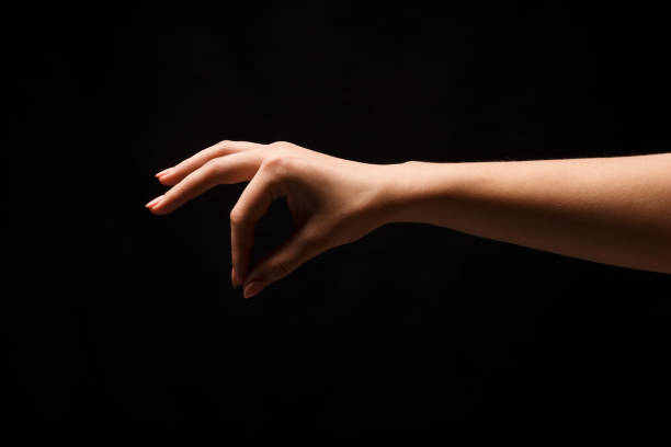 istock Female hand picking up something, cutout at black 909927680