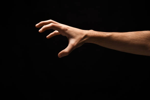 istock Male hand picking up something, cutout on black 909928110