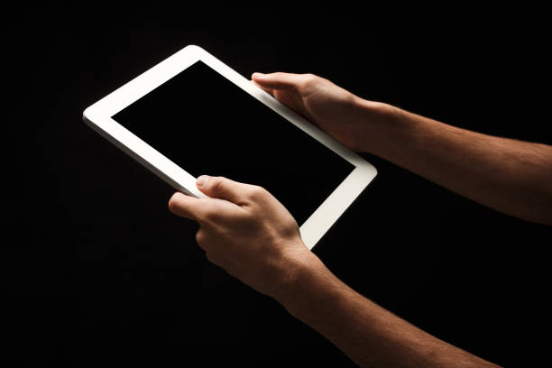 istock Man holding tablet with blank screen at black background 909931172