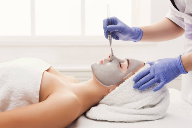 istock Woman gets face mask by beautician at spa 909931434