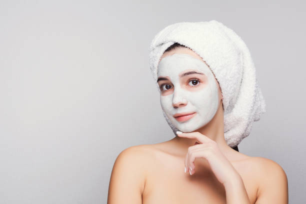 istock Beautiful girl with applied clay mask at white background 909931540