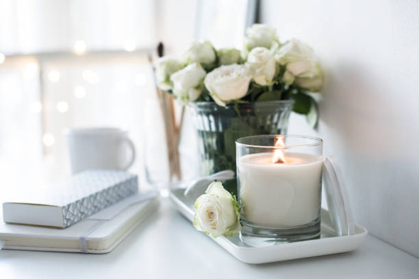 White room interior decor with burning hand-made candle and bouq White room interior decor with burning hand-made candle and bouquet of fresh roses on table, luxury home decorations in daylight closeup luxury craft stock pictures, royalty-free photos & images