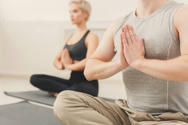 istock Young couple practicing yoga sitting in padmasana 909932060