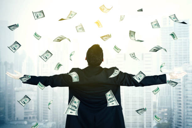 Young businesswoman with dollar money Young businessman outstretched his arms while standing under dollar money falling from the sky with skyscraper background falling behind stock pictures, royalty-free photos & images