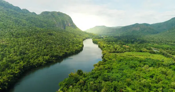 Beautiful natural scenery of river in southeast Asia tropical green forest  with mountains in background, aerial view drone shot