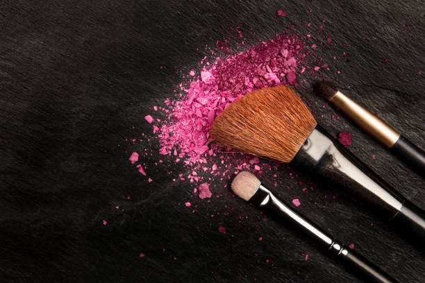 istock Closeup of makeup brushes with eye shadow on black with copy space 909938556