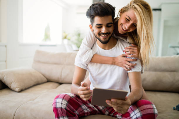 istock Happy couple in love using tablet in pajamas 909939346