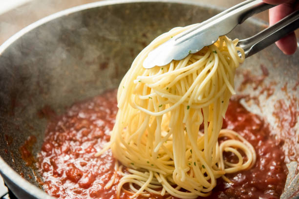 spaghetti messi in padella con salsa alla bolognese calda - sugo pronto foto e immagini stock