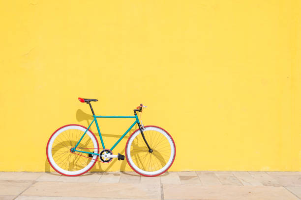 городской велосипед фиксированной передач на желтой стене - bicycle cycling bicycle pedal part of стоковые фото и изображения