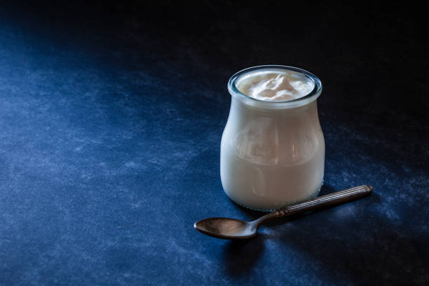Yogurt in a glass container shot on bluish tint background