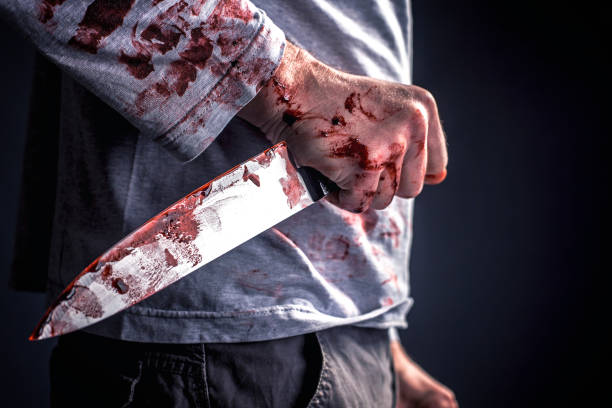 Midsection Of Murderer Holding Blooded Knife Against Black Background  murderer stock pictures, royalty-free photos & images