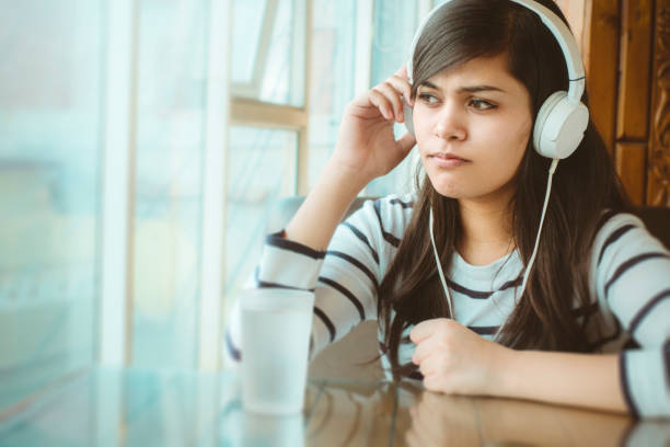 istock Single young woman listening podcast. 909980056