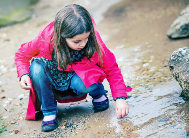 istock kid playing on a rock at the water's edge 909984314