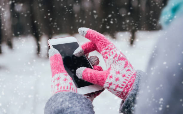 istock Woman using smartphone in winter with gloves for touch screens 909987542