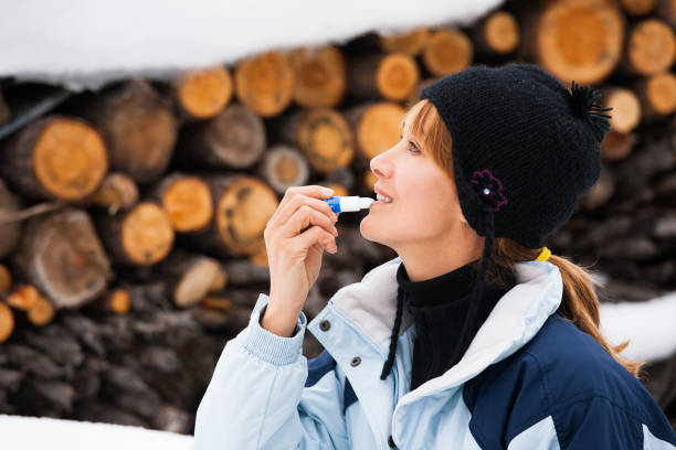 istock woman in winter who puts sunscreen on her lips 909987548