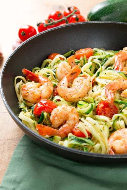 istock Zucchini noodles sauteed with cherry tomato and prawns in a pan 909987612
