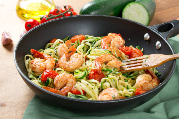 istock Zucchini noodles sauteed with cherry tomato and prawns in a pan 909987634