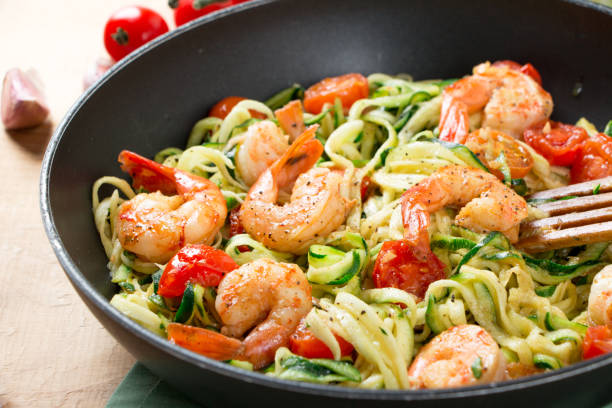 istock Zucchini noodles sauteed with cherry tomato and prawns in a pan 909987662