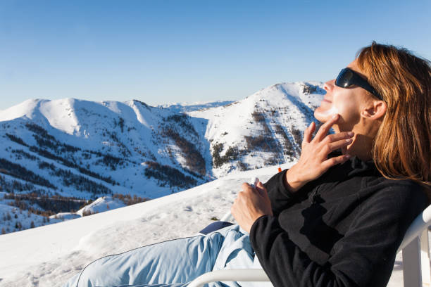woman with snow who puts sunscreen on her face