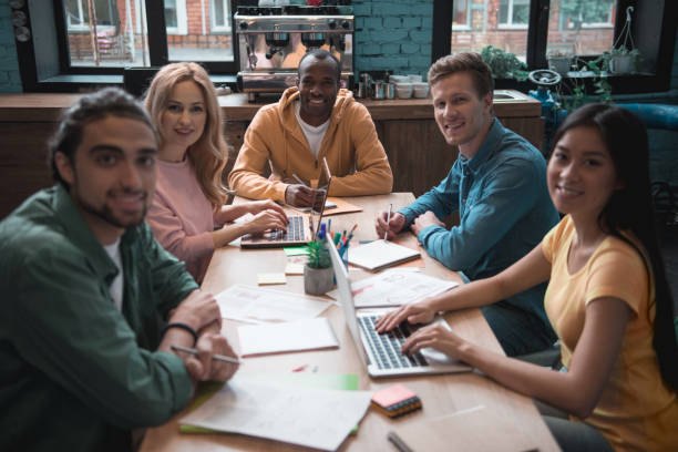 istock Cheerful group of people working at desk 909990792