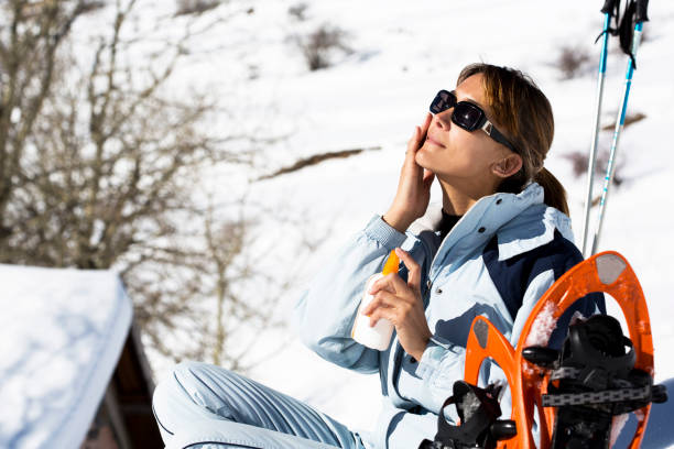 женщина со снегом, который ставит солнцезащитный крем на ее лице - snowshoeing hiking mountain winter стоковые фото и изображения