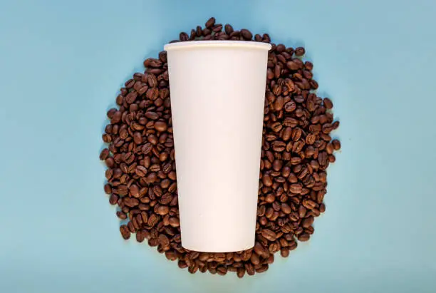 White paper glass lies on coffee beans. Mock up