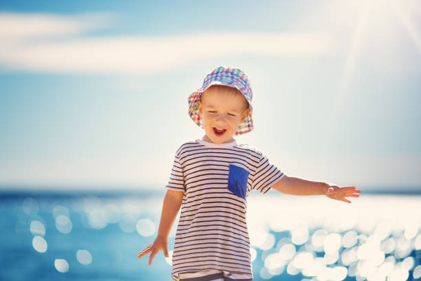 istock happy boy smiling at the beach in hat 909994016